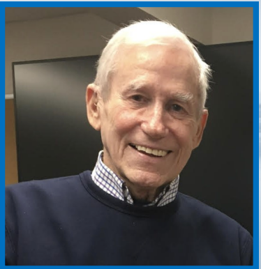 White haired gentleman wearing a shirt and sweater